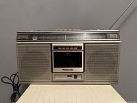 Front view of the Panasonic RX-5020 radio cassette player showing speakers, cassette compartment, radio dial, and power cord.