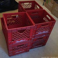 Seven red plastic milk crates stacked and arranged in a group, showing the Sealtest logo on the side.