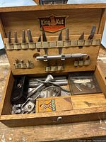Overall view of the hobby tool kit laid open, showing tools inside the wooden box including blades, handles and hand tools.