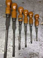 Set of seven Clay Sheffield cabinetmaker screwdrivers laid out on a surface, showing different blade sizes and wooden handles.