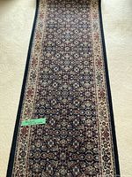 Full view of carpet runner placed on cream carpet, showing blue field with floral pattern and cream border.