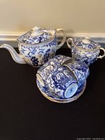 Overall view of teapot, sugar bowl, four cups and four saucers on black surface