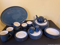 Navy and white Denby dishes arranged on table including plates, mugs, bowls, saucers, salt and pepper shakers, and a navy teapot not marked Denby.