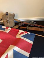 Photo showing the Union Jack flag partially rolled out alongside a military canteen and two replica pistols.
