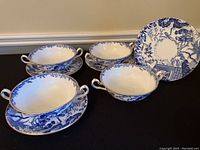 Three cups and three plates arranged on black surface showing the blue Mikado pattern and gold trim.