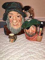 Set of three Royal Doulton Toby mugs including large Smuggler jug, medium pirate-themed jug, and small miniature mug.