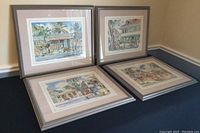 Four framed and matted prints depicting different Barbados street scenes by Jill Walker, circled on a dark surface.