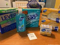 Image showing all soap packages and body wash bottle on a table: Lever 2000 bar soap 10-pack, Zest 10-pack, two 8-packs of Dial bar soap, 3-pack Dial bar soap, and Dial Spring Water body wash