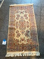 Full view of the hand knotted wool carpet laid flat showing floral pattern and fringes.