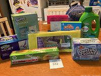 Photo showing all cleaning supplies including Swiffer Sweeper and WetJet refills, EZGreen mop pads, ShopRite dusting cloths, clothespins, Mr. Clean Magic Eraser, Cascade dishwasher liquid, and food storage bags arranged on table.
