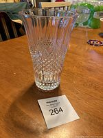 Clear vintage crystal vase standing on a wooden table, showing the full body with diamond and geometric cut patterns. The vase height is approximately 7.5 inches and it features a fluted top.