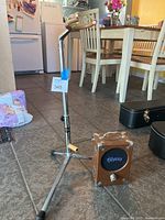 Photo showing the Pignose 7-100 amplifier and the SRO adjustable guitar stand together on the floor in a kitchen environment.