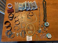 Overview of the entire lot displayed on a wooden surface including multiple bracelets, necklaces, earrings, watches, and a pair of decorative boxes.