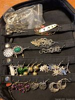 Top view of jewelry items including earrings of different styles and colors arranged inside the zippered case