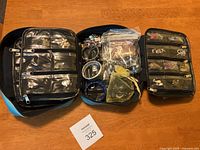 Full view of three zippered jewelry organizer cases on wooden table displaying assorted jewelry items including bracelets and earrings.