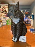 Front view of the dark brown tabby cat sculpture showing its upright seated position and white chest patch.