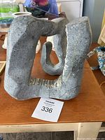 Front view of the abstract stone sculpture showing its rough texture and organic form.