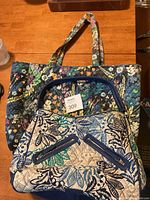 Both Vera Bradley bags displayed on a wood surface showing size comparison and patterns