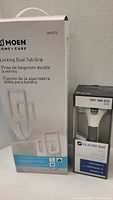 Photo of Moen Locking Dual Tub Grip box showing product image and details, next to Glacier Bay Suction Assist Bar packaging.