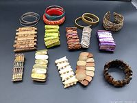 Photo showing all bracelets arranged on a black surface, various styles including bangles, cuff bracelets, and beaded bracelets