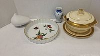Full view of the lot showing the soup bowl with lid, pie plate with fruit design, Delft blue and white vase, and white Rosenthal vase.