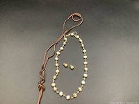 Full view of the pearl necklace and matching earrings on black background showing size and general look