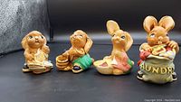 Four Pendelfin bunny figurines lined up showing different chores each bunny is doing