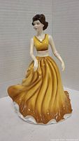Porcelain figurine named Karen, approximately 9 inches tall, wearing a golden-yellow dress with white accents.