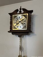 Close-up of Citizen cuckoo clock face and wooden frame showing decorative elements and chains with weights.