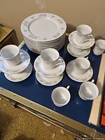 Arranged teacups and saucers with floral pattern and silver trim