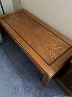 Walnut veneer coffee table showing wood grain pattern and inlay on top surface with sturdy legs on carpet