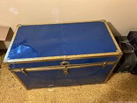 Blue metal hope chest with brass corner reinforcements and lockable latches.