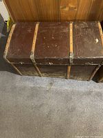 Vintage brown leather hope chest with metal reinforcements and signs of wear; rectangular with rounded top