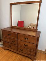 Front view of the vintage wood veneer dresser with an attached mirror and six drawers, showing the wood finish and handle details.
