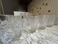 Ten short crystal glasses arranged on a marble countertop, showcasing the pinwheel cut pattern and overall set quantity.