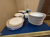 Assorted dinner plates stacked on one cart shelf with some smaller bowls and cups