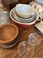 Wide view of stacked ceramic bowls, wooden bowls, and cut-glass bowls on a table near vintage phone.