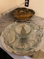 Full view showing both serving trays, glass in front and ceramic flower-shaped on metal stand behind, set on kitchen counter