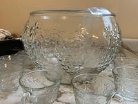 Textured glass punch bowl with 3 small glasses in front, showing bubble-like textured pattern