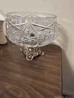 Crystal fruit bowl with ornate metal base on wooden surface
