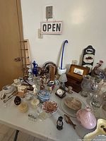 Wide shot showing an assortment of vintage trinkets, including glassware, figurines, small clocks, and decorative items on a tabletop.