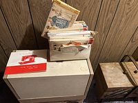 Photo of vintage sewing patterns in a white holder placed on top of the sewing machine case alongside the manual.