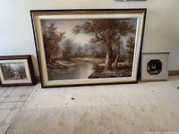 Large print with river and trees in black and gold frame