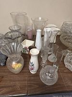 Overview of assortment of vases in glass, crystal, and ceramic material on table showing variety in shape and size.