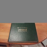 Rand McNally Universal World Atlas book closed, showing green cover with gold lettering.
