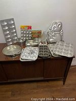 Wide-view showing all bakeware items including pans, molds, and icing tools arranged on a table