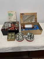 Full lot including the boxed Cooky-Pastry Press, lattice pastry roller box, storage tin with cookie cutters, and additional loose cutters on table.