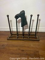 Front view of metal boot dryer stand with a boot on one rod.