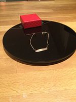 Rose gold box chain bracelet with an engraved rectangular plate displayed on a black tray with a red box.
