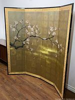 Front view of the 4-panel hand-painted screen showing gold-tone background with blossom and bird artwork and two visible dents on the front panels.